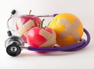 Bandaged apple tomato and orange with stethescope to promote good health